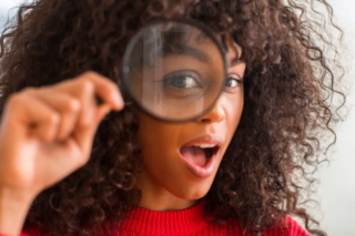 Woman Looking Through Magnifying Glass Excited To Have Found Something 1 930x620.jpg